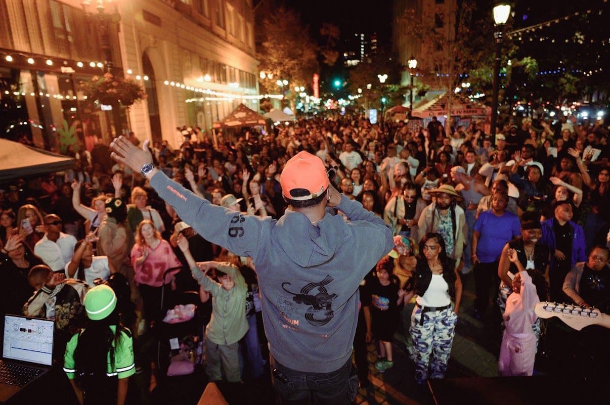 Oke on stage facing a packed street crowd at night